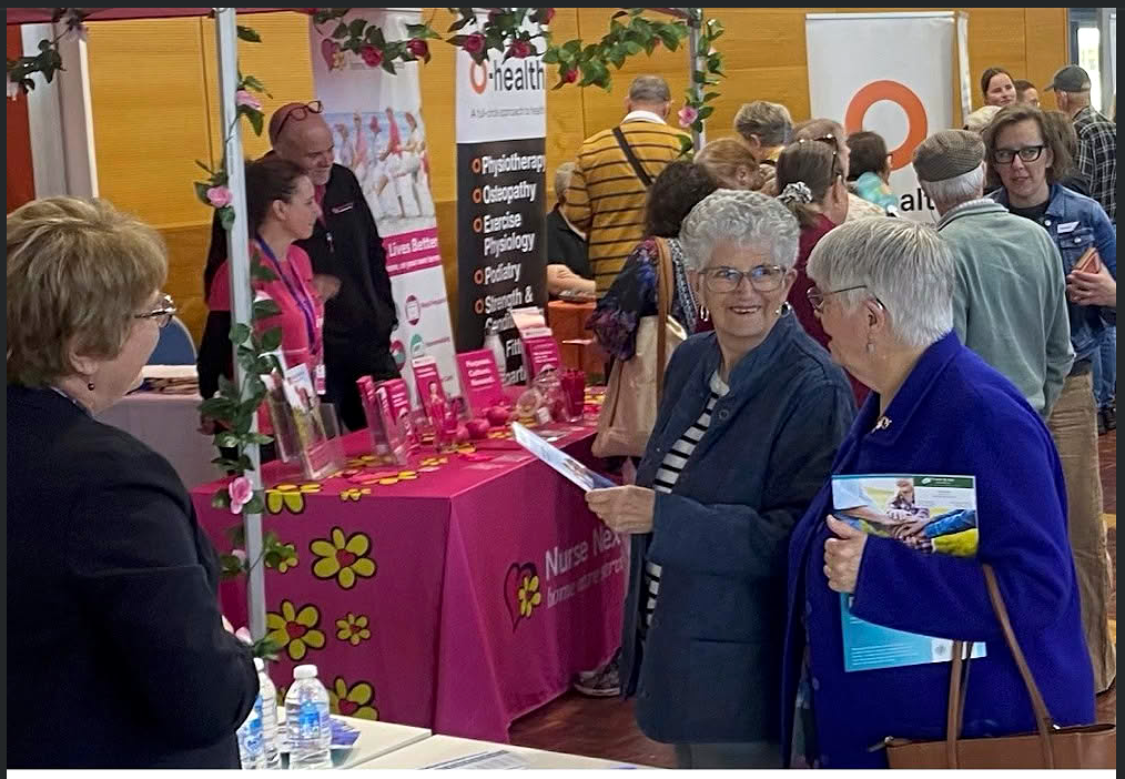 Older visitors enjoying friendly conversations with service providers at a busy Senior Expo